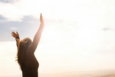 Person relieved, holding their hands up in the air on a sunny day