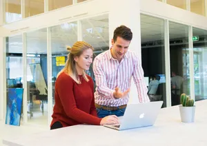 Colleagues happily using a laptop in the office