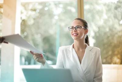 Lady smiling whilst passing over paperwork